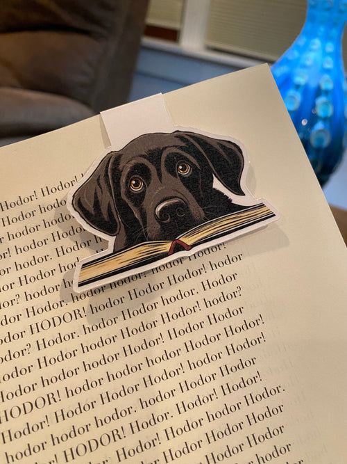 Black labrador magnetic bookmark clipped onto an open paperback book