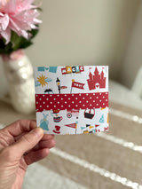 Folded tri-fold handmade birthday card with red polka-dot belly band, castle and 'Magic' illustration