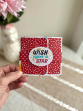 Pop-up gift bag detail with red polka-dot pattern and 'Wish Upon a Star' label